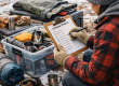 Camper organizing camping gear during winter while using a checklist to prepare for spring camping season
