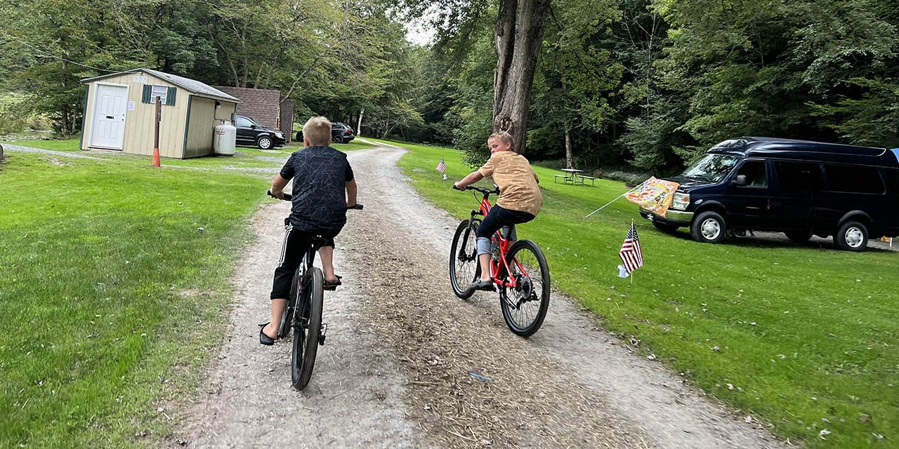 Children riding bicycles through Stony Fork Creek Campground during a summer family camping vacation