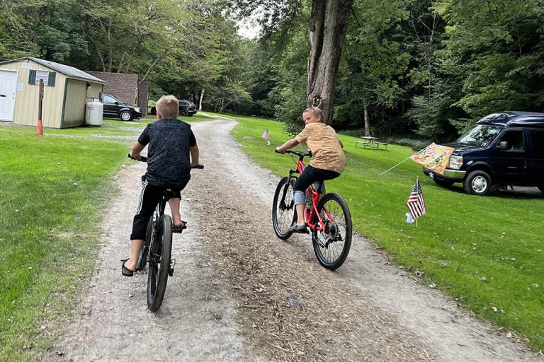 Children riding bicycles through Stony Fork Creek Campground during a summer family camping vacation